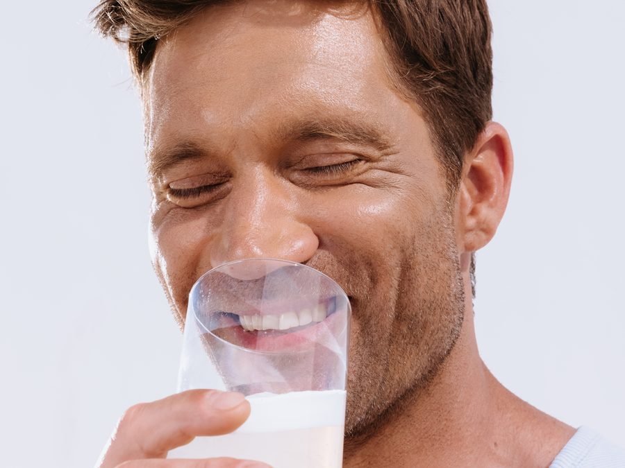 A man smiling with his eyes closed as he drinks a glass of mixed ARMRA Colostrum